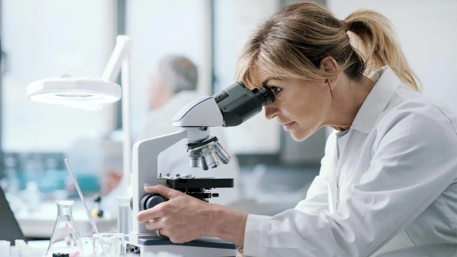 Doctor in a white coat at a laboratory microscope
