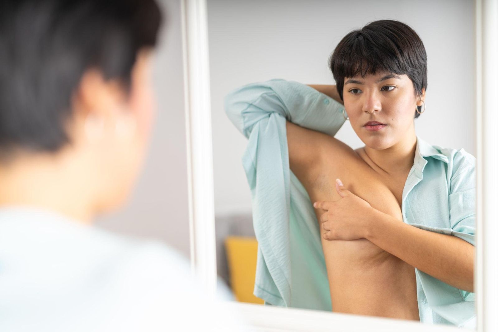 Femme s'observant dans le miroir, examen visuel des seins